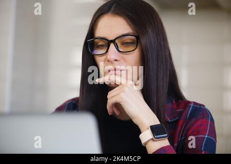 Freelancer woman thinking about problem solution. Young entrepreneur person working on computer. Portrait of white female in thought about work Stock Photo