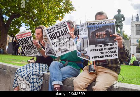 London, England, UK. 3rd Oct, 2022. Just Stop Oil protesters read mock newspapers in Parliament Square. The protest is part of a series of demonstrations taking place daily in Westminster, with the climate action group demanding an end to fossil fuels and a switch to renewables. (Credit Image: © Vuk Valcic/ZUMA Press Wire) Stock Photo