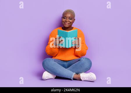 Full body photo of cheerful charming lady sitting floor hold book isolated on violet color background Stock Photo