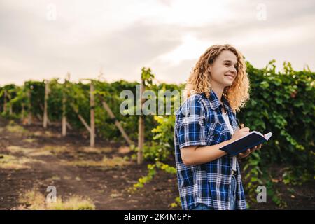Woman engineer holding a note book examining agricultural plantation. Smart agriculture. Natural summer landscape. Harvest concept. Green nature Stock Photo