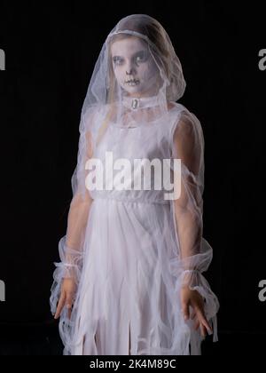 Little girl in Halloween ghost costume looking at camera, studio isolated on black background Stock Photo