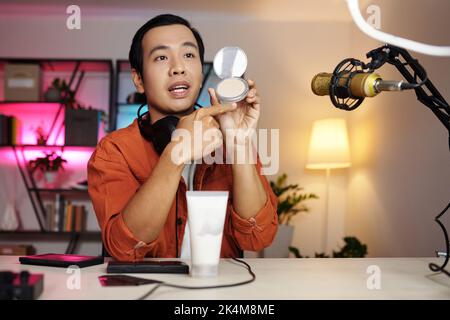 Horizontal medium portrait of modern Asian male beauty blogger making review or advertisment for new cosmetic products Stock Photo