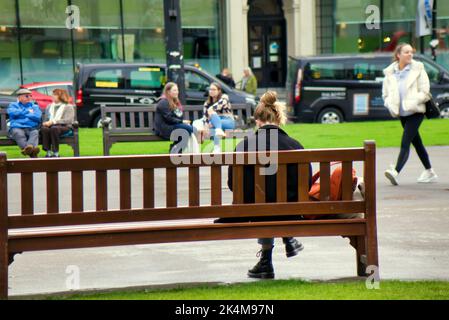 young girl sitting  on bench in george square Glasgow, Scotland, UK Stock Photo