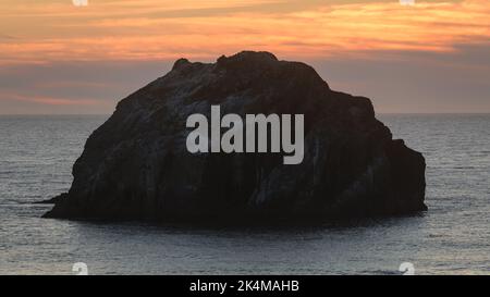 Iconic Face Rock in the water of the Pacific Ocean off Bandon Oregon during sunset Stock Photo