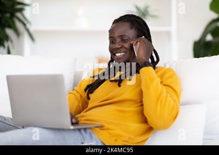 Young Black Male Freelancer Working With Laptop And Cellphone At Home Office Stock Photo