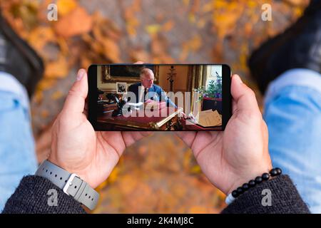 Belgrade, Serbia - October 03, 2022: Watching on smartphone King Charles III performing official business at Buckingham Palace in London, United Kingd Stock Photo