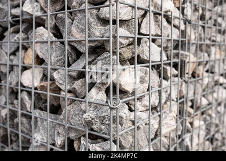 corner part of a mesh fence filled with stones Stock Photo