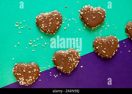 chocolate cookies hearts with nuts on colorful background. flat lay on colored paper. Chocolate chips Stock Photo