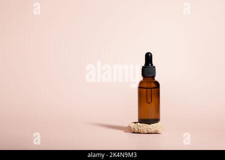 Amber glass dropper bottles for serum on stone on beige background Stock Photo