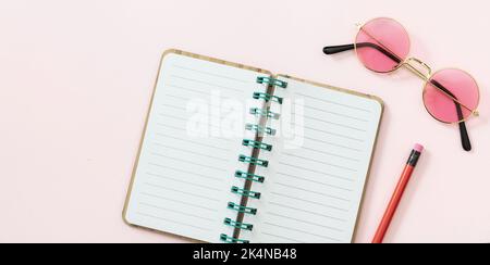 Open diary blank paper, pencil, sunglasses on pink background. Blank spiral notepad, copy space, top view Stock Photo