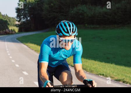 Male professional road cyclist during a race with mad and exhausted face Stock Photo
