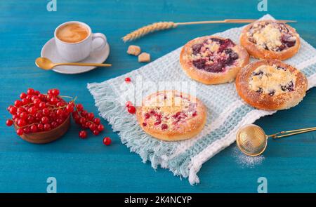 Baked pies with summer fruits, currants, plums, blackberries, blueberries and crumble on blue wooden table, high angle of view, no people. Stock Photo