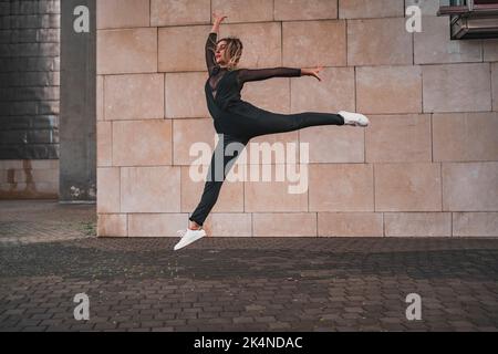 Young girl doing gymnastic jump on the street. Stock Photo