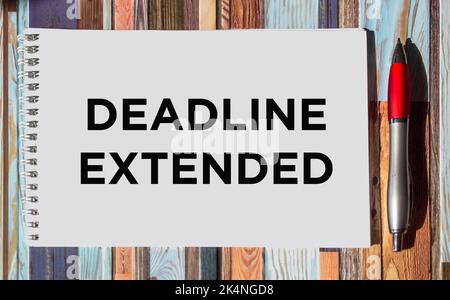 Business and finance concept. The phrase DEADLINE EXTENDED is written on a notepad with a pen on a vintage background Stock Photo