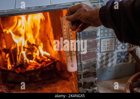 London, UK. Sept 29 2022 .Close up of hand holding a thermometer measuring temperature of fireplace . Stock Photo