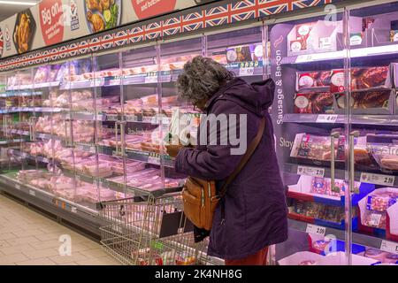 London, UK. Sept 29 2022 .A woman shopper checking out the price of oven ready meal on a refrigeration food shelf in Lidl store in Lewisham,London . Stock Photo