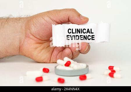 Medical concept. On a white background, medical capsules, in the hands of a person a paper plate with the inscription - Clinical Evidence Stock Photo
