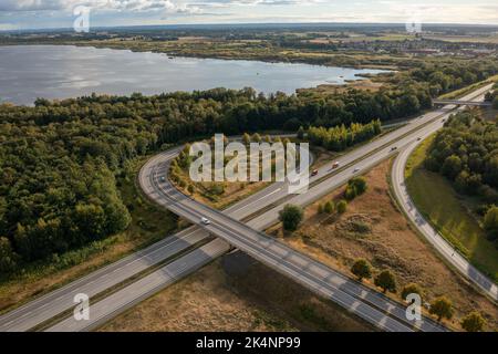 An aerial shot of a curved highway surrounded by dense vegetation Stock Photo