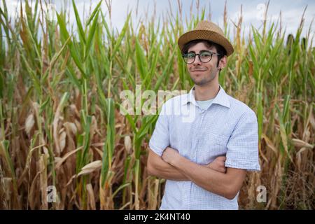 Smiling farmer with his hands crossed in front of his corn field, soon the corn will be ready for harvest. Stock Photo