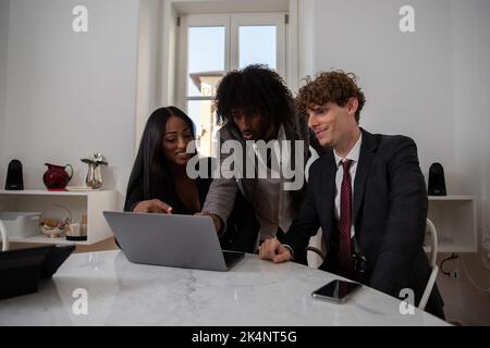 Group of three colleagues in the office discussing a topic, work in front of the computer. Stock Photo