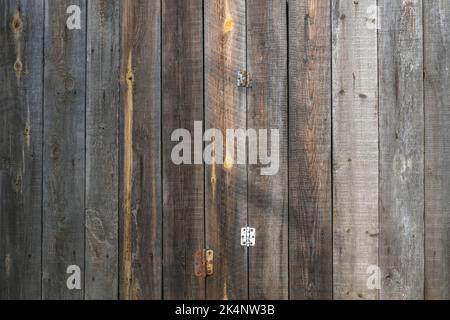 The texture of an old fence with a shadow. Wood texture with vertical lines. The texture of wood with knots and holes. The background of a fence damaged by time. Stock Photo
