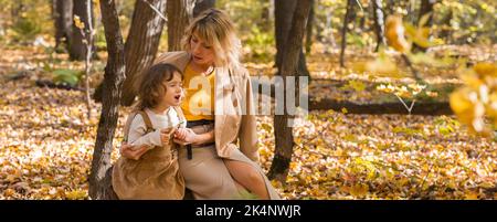 Banner mother comforting her crying little girl in autumn nature copy space. Emotions and family concept. Stock Photo