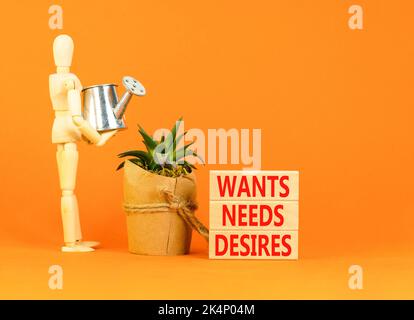 Wants needs and desires symbol. Concept words Wants Needs Desires on wooden blocks. Businessman model. Beautiful orange background. Business, psycholo Stock Photo