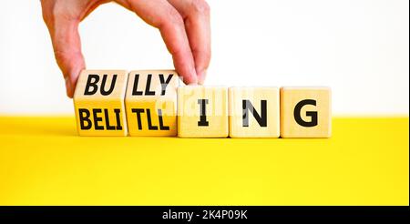 Bullying and belittling symbol. Concept words Bullying and Belittling on wooden cubes. Businessman hand. Beautiful yellow table white background. Busi Stock Photo