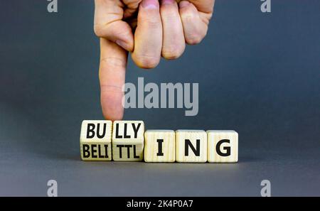 Bullying and belittling symbol. Concept words Bullying and Belittling on wooden cubes. Businessman hand. Beautiful grey table grey background. Busines Stock Photo