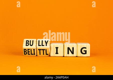 Bullying and belittling symbol. Concept words Bullying and Belittling on wooden cubes. Beautiful orange table orange background. Business bullying and Stock Photo