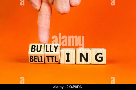 Bullying and belittling symbol. Concept words Bullying and Belittling on wooden cubes. Businessman hand. Beautiful orange table orange background. Bus Stock Photo