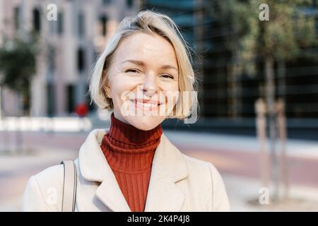 Young beautiful mid adult business woman smiling at camera outdoors Stock Photo