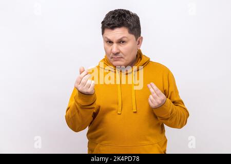 Portrait of handsome middle aged man standing and looking at camera with money or italian gesture with hand, wearing urban style hoodie. Indoor studio shot isolated on white background. Stock Photo