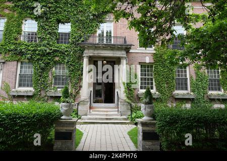 Brick wall building of the faculty club university of toronto, covered with climbing ivy plant. Entrance to the building Stock Photo