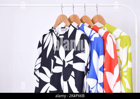 Multi colored female shirts with striped on hangers against a white background. Stock Photo