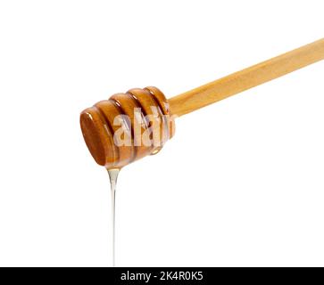 Honey and wooden honey dipper on white background. Honey dripping from honey dipper. Close-up. Stock Photo