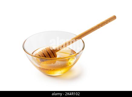Honey in glass bowl and wooden honey dipper on white background. Stock Photo