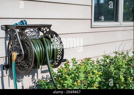 Decorative metal hose storage wheel mounted on the exterior of a  residential house Stock Photo - Alamy
