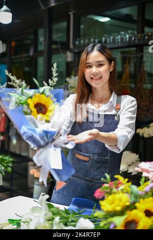 Portrait, Elegant young Asian female florist or flower shop worker holding a beautiful flower bouquet. Small business startup concept Stock Photo