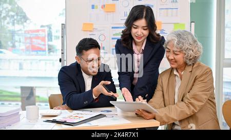 Professional Asian senior businesswoman or female boss in the meeting with her financial analysts team, discussing and analyzing their business financ Stock Photo