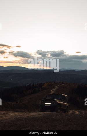 Car truck is going up on road in mountains during autumn evening Stock Photo
