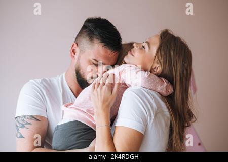 Happy multinational family father young man and mother with baby girl little daughter having fun in children room at home Stock Photo