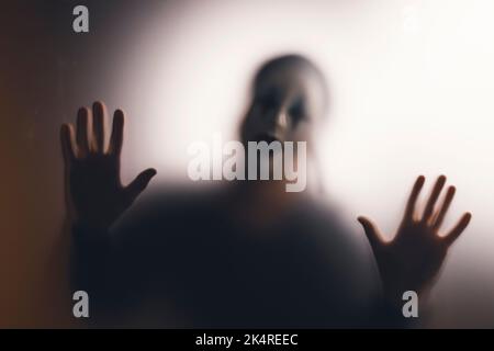 Horror ghost woman behind the matte glass. Halloween festival concept. Stock Photo