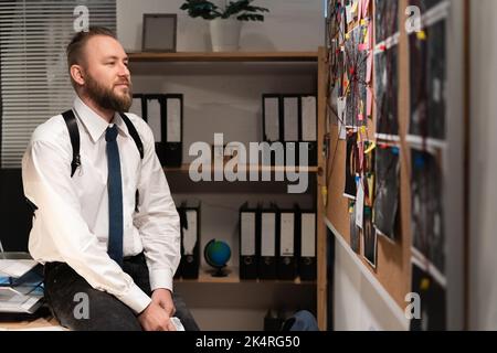 Detective looking at evidence board in office, working at night Stock Photo