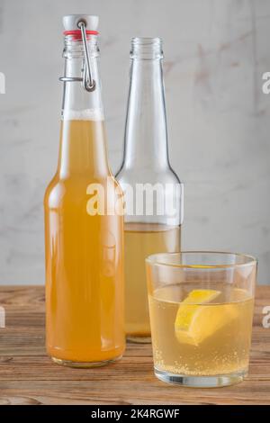 The glass of Kombucha drink with lemon and two bottles. Vertical orientation. Stock Photo