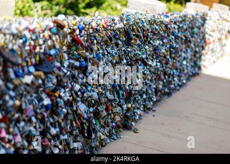 Old and new padlocks with names and dates written on them lock on a bridge as a sign of love in San Antonio, Texas. Stock Photo