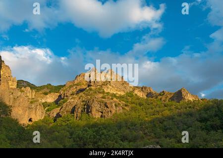 Rocky and forested mountains near Geghard monastery, on a sunny and cloudy day, at sunset, during golden hour Stock Photo