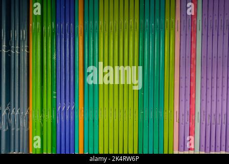 Colorful notebooks on the shelf at bookshop. A lot of books with bright covers in one pile. Design element, paper and leather texture. Stock Photo