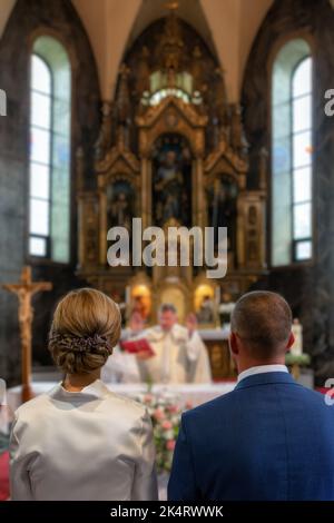 Newlyweds standing in front of the altar. Priest givin a  blessing. Stock Photo