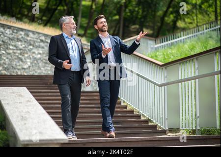 Two businessmen walking down the stairs and talking Stock Photo